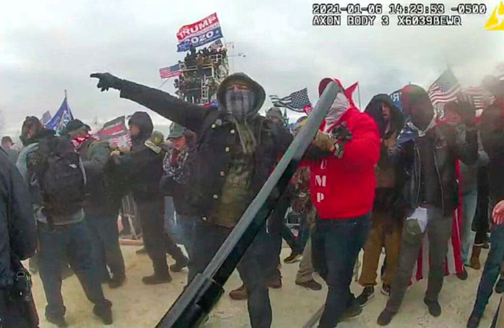 This image, from the criminal complaint, shows a Brian Christopher Mock, center, in an image captured in police body worn video on the West Front of the U.S. Capitol in Washington, on Jan. 6, 2021. (Justice Department via AP)