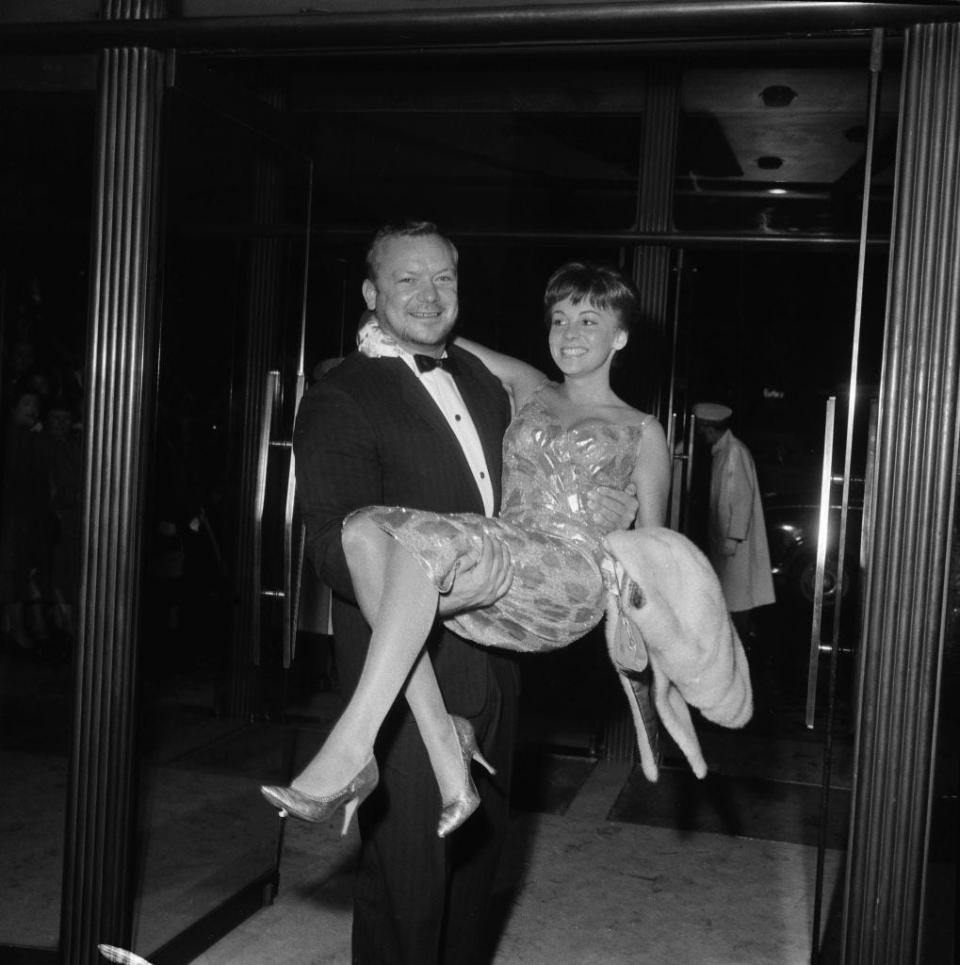 American actor Aldo Ray (1926 - 1991) carrying his wife Johanna at the London premiere of his new film 'The Day They Robbed the Bank of England', May 18th 1960.