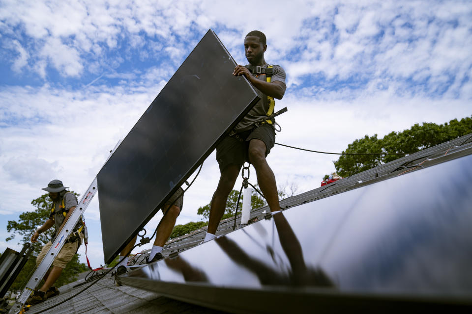 FILE - Employees of NY State Solar, a residential and commercial photovoltaic systems company, install an array of solar panels on a roof, Aug. 11, 2022, in the Long Island hamlet of Massapequa, N.Y. The Biden administration is announcing Thursday, April 20, 2023, more than $80 million in funding as part of a push to make more solar panels in the U.S. and make solar energy available in more communities. (AP Photo/John Minchillo, File)