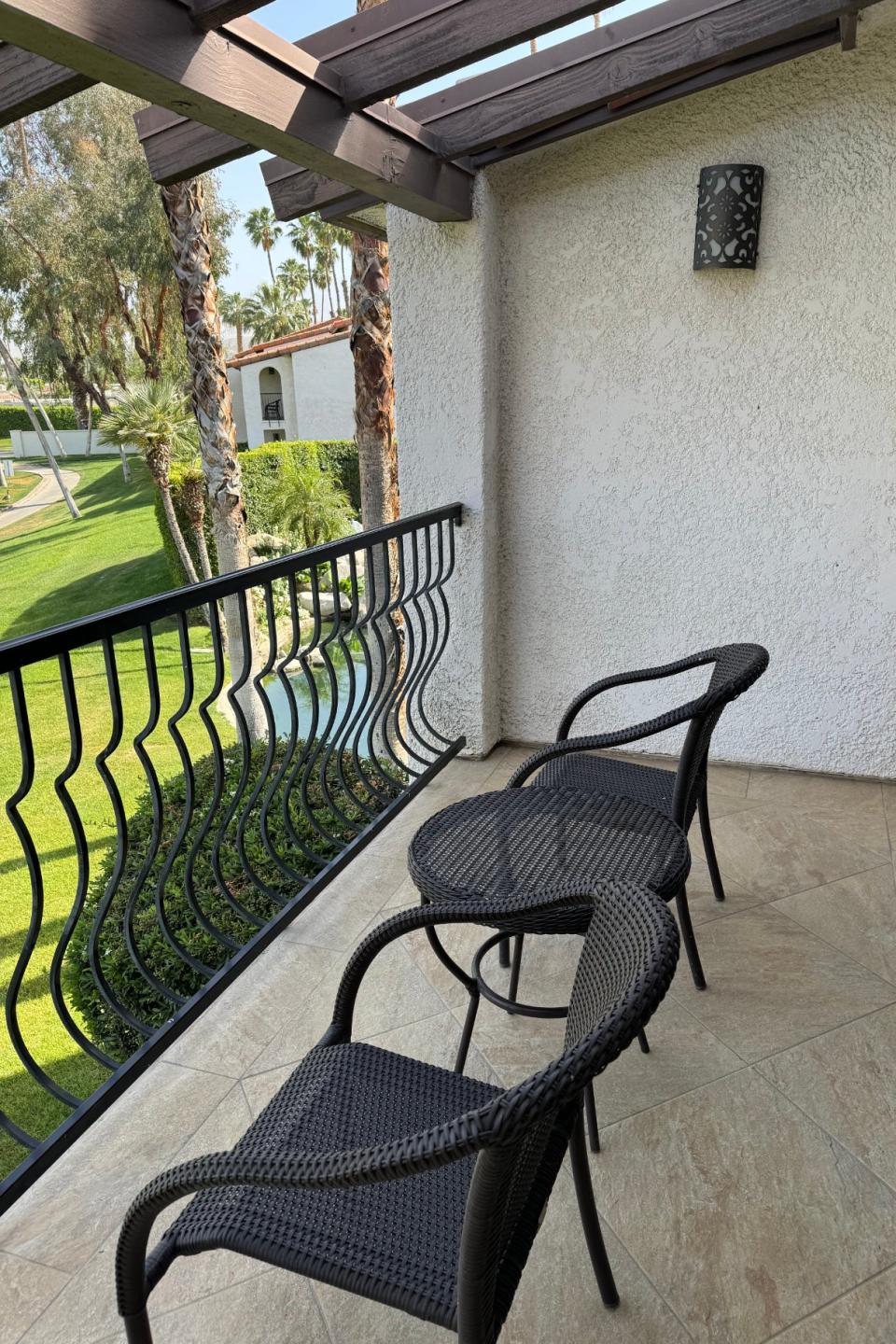 Balcony with two chairs overlooking a landscaped area, suggesting a relaxing spot at a travel destination