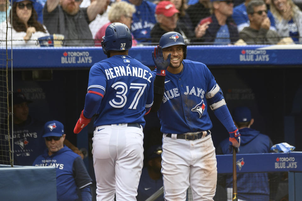 Toronto Blue Jays outfielder Teoscar Hernandez (37) celebrates with teammate George Springer after scoring on a single by catcher Danny Jensen during the second inning of a baseball game against the Boston Red Sox in Toronto on Saturday, Oct. 1, 2022. (Christopher Katsarov/The Canadian Press via AP)