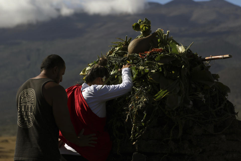 FILE - In this July 14, 2019 file photo, native Hawaiian activists pray at the base of Hawaii's Mauna Kea pictured in background. A leading Spanish official said Monday Aug. 5, 2019, that the consortium pushing to build a giant telescope in Hawaii amid continued protests by locals is planning to ask for a building permit for an alternative site in Spain's Canary Islands. The notification comes as Native Hawaiian protesters enter the fourth week of blocking construction of the telescope on a mountain they consider sacred. (AP Photo/Caleb Jones, File)