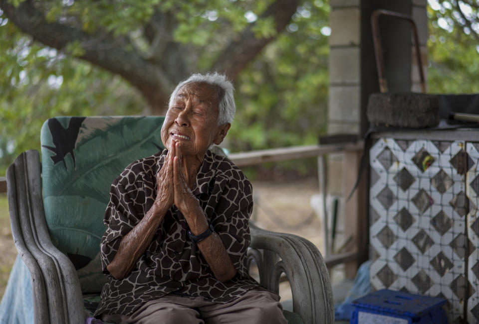 Meli Watanuki talks about praying to the Catholic Saints, Father Damien and Mother Marianne, while sitting on her porch on Wednesday, July 19, 2023, in Kalaupapa, Hawaii. In the 1800s, the peninsula was a settlement for banished leprosy patients, later called Hansen's disease. (AP Photo/Jessie Wardarski)