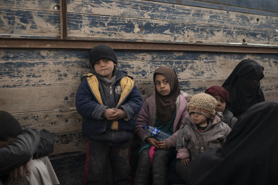 Women and children wait to be screened by U.S.-backed Syrian Democratic Forces (SDF) after being evacuated out of the last territory held by Islamic State militants, in the desert outside Baghouz, Syria, Wednesday, Feb. 27, 2019. (AP Photo/Felipe Dana)