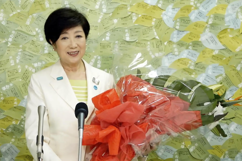 In this image made from YouTube provided by Koike Yuriko Official Channel, Tokyo Gov. Koike recieves a bunch of flower from supporter during her gubernatorial election victory press conference at her election office in Tokyo, Sunday, July 5, 2020. (Koike Yuriko Official Channel via AP)