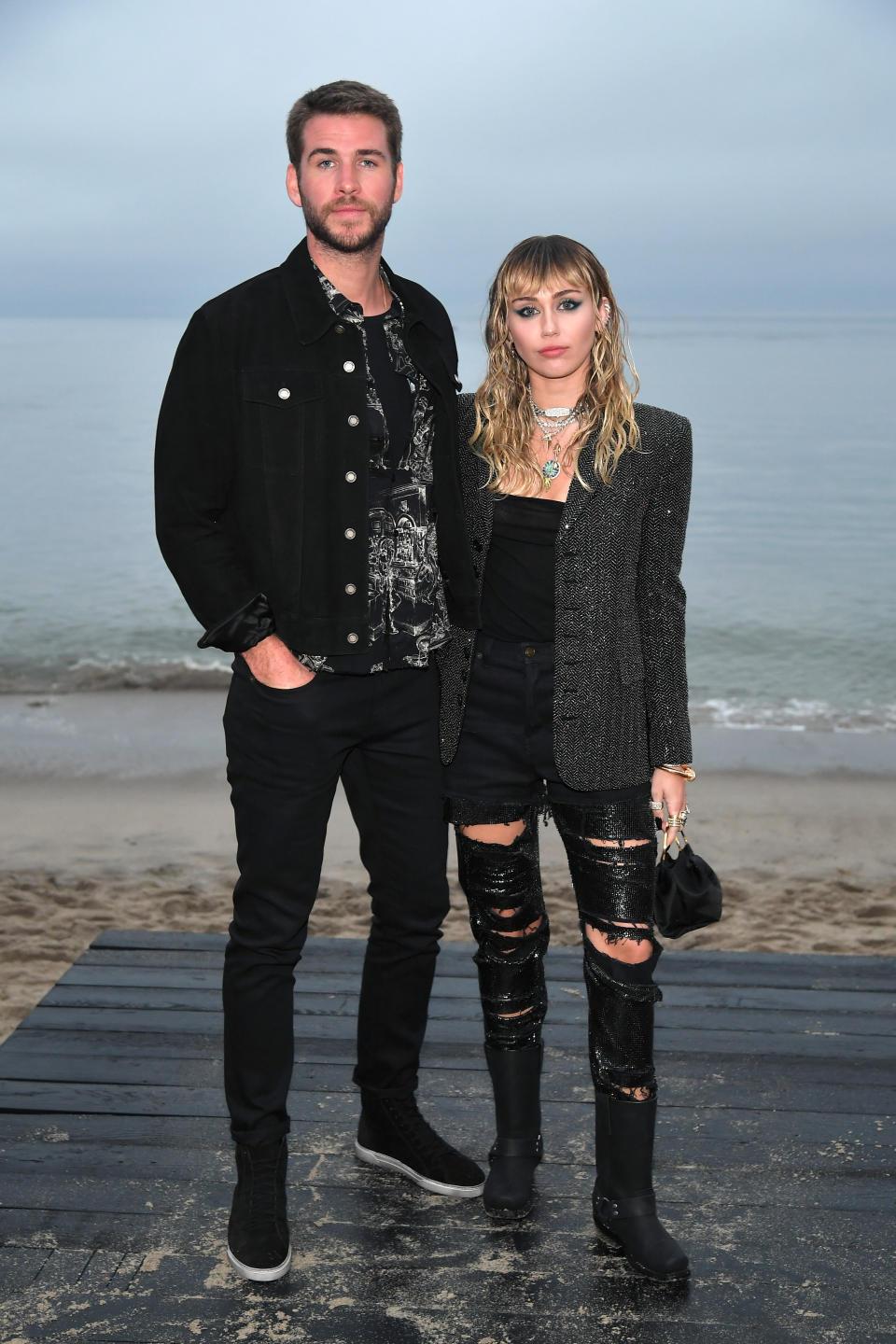 Miley Cyrus and Liam Hemsworth in black clothes at the beach