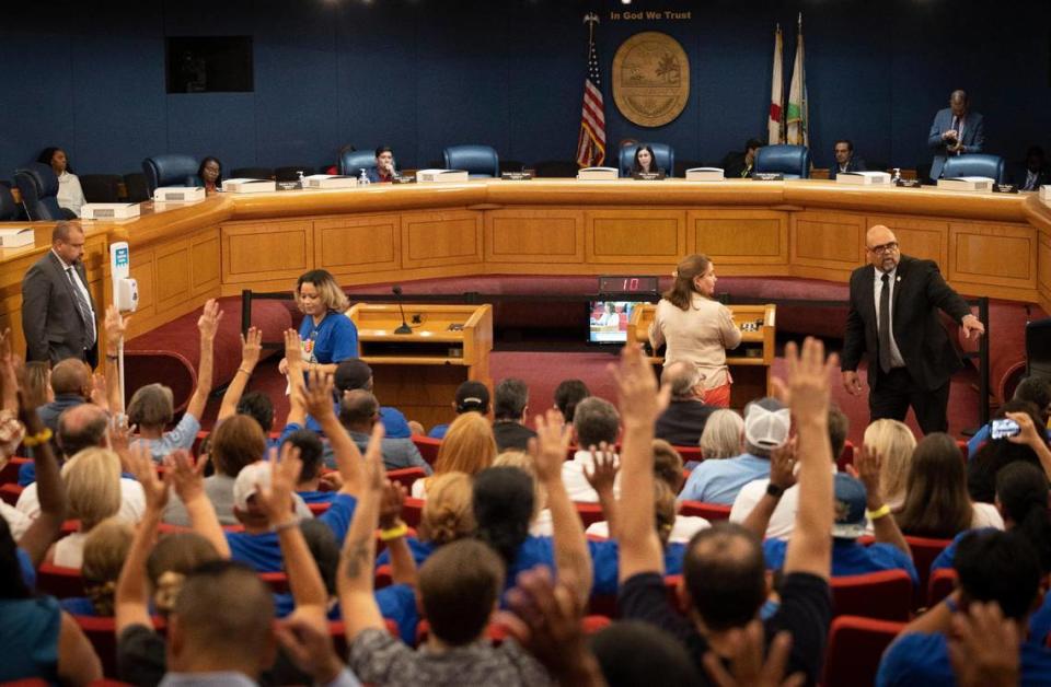 Personas levantan la mano en apoyo del estándar contra el calor de Miami-Dade para los trabajadores al aire libre durante una reunión del Comité de Salud Comunitaria de la Comisión del Condado Miami-Dade antes de la votación, el lunes 11 de septiembre de 2023, en el Centro de Gobierno, en Miami. El proyecto de ley crearía protecciones para los trabajadores al aire libre en días calurosos, como agua, sombra y descansos.