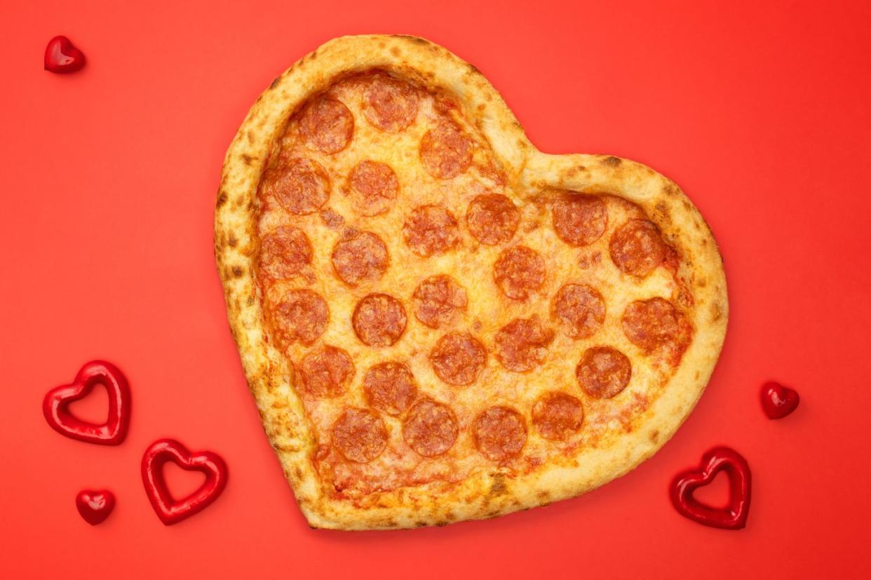 heart shaped pizza pepperoni for valentines day on red paper background