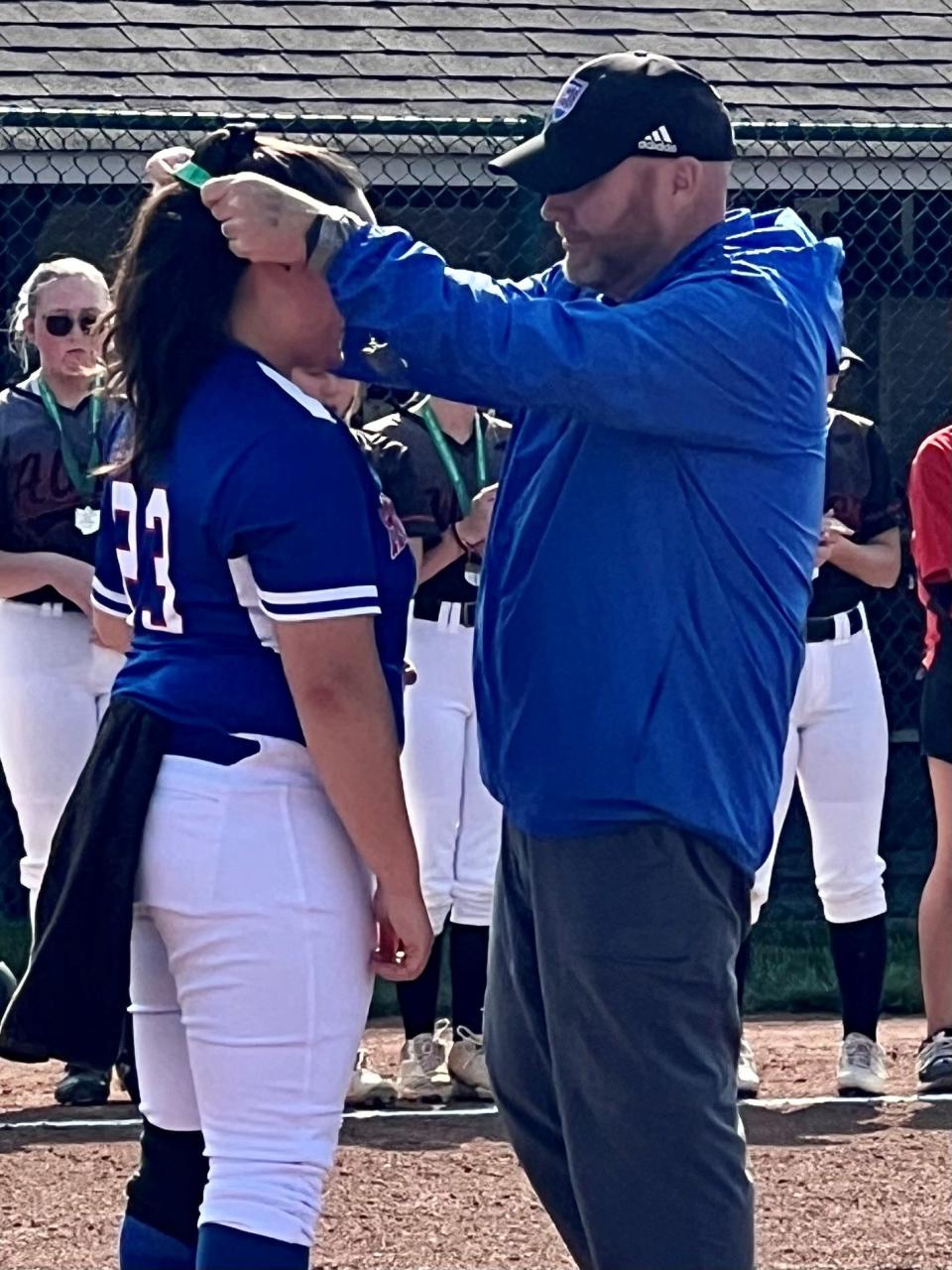 Highland Athletic Director Mike DeLaney puts the Division II softball district championship medal around the neck of senior pitcher Stevie Asher Saturday at Pickerington.