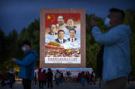 Visitors take photos on a public square at the base of the Potala Palace near a large mural depicting current and former Chinese leaders, clockwise from top, Mao Zedong, Deng Xiaoping, Hu Jintao, Xi Jinping, and Jiang Zemin, in Lhasa in western China's Tibet Autonomous Region, as seen during a rare government-led tour of the region for foreign journalists, Tuesday, June 1, 2021. Long defined by its Buddhist culture, Tibet is facing a push for assimilation and political orthodoxy under China's ruling Communist Party. (AP Photo/Mark Schiefelbein)