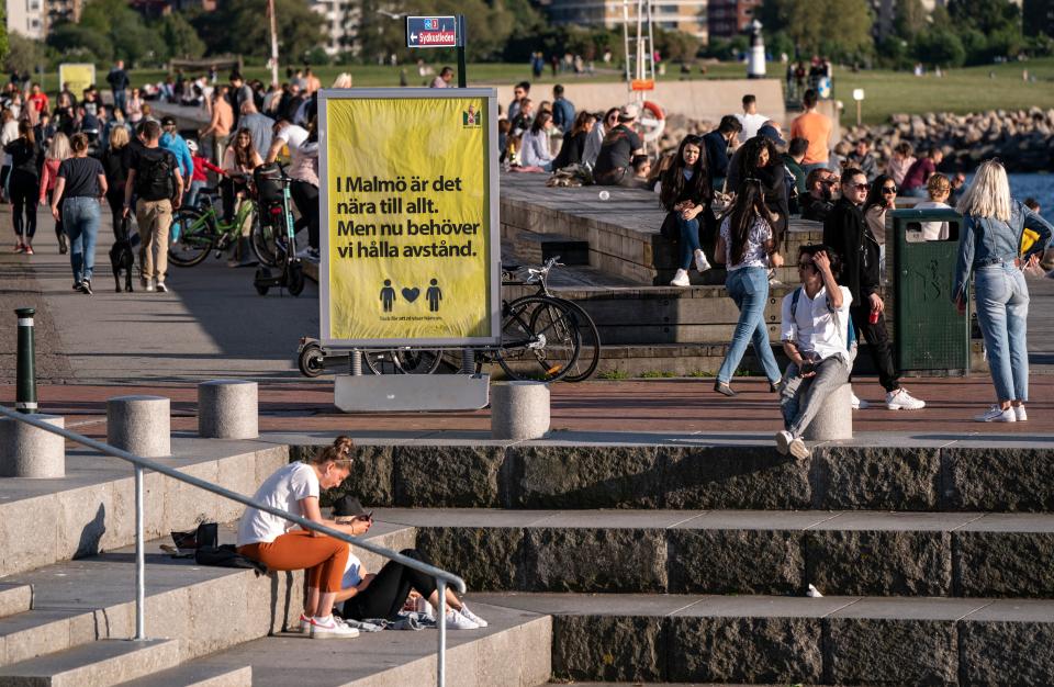 People enjoy the warm evening at Sundspromenaden in Malmo, Sweden, on May 26, 2020, amid the coronavirus pandemic. - The sign reads 'In Malmo everything is near. But now, we need to keep distance'. (Photo by Johan NILSSON / TT News Agency / AFP) / Sweden OUT (Photo by JOHAN NILSSON/TT News Agency/AFP via Getty Images)