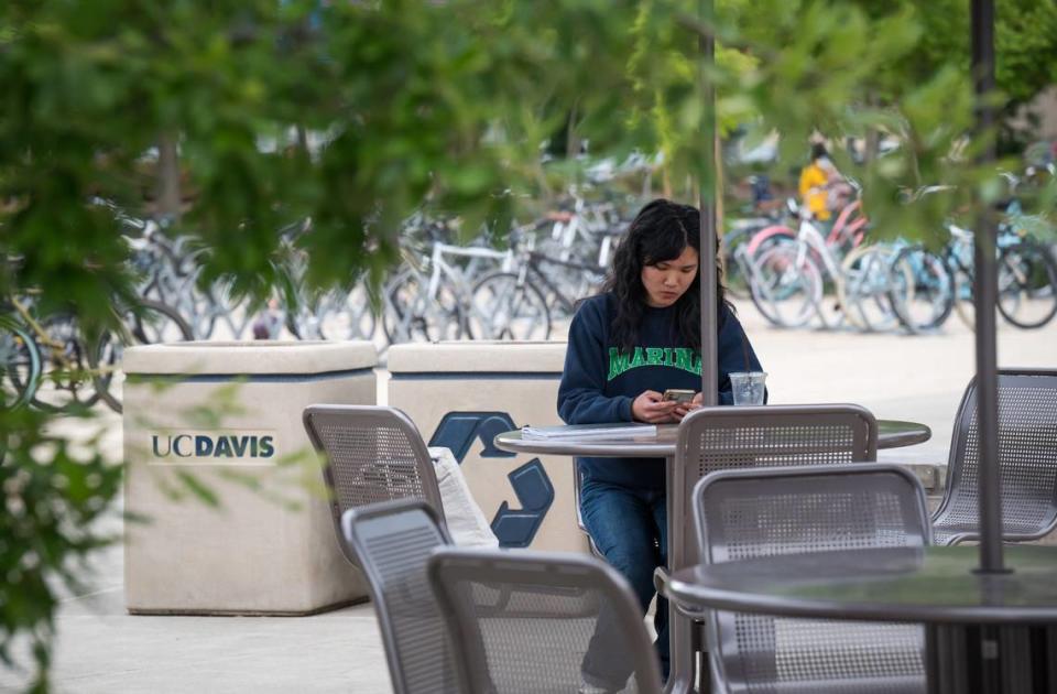 UC Davis second-year chemistry student Isabella Pham sits at a table on campus as she watches a streaming news conference Thursday, May 4, 2023, in which Davis police Chief Darren Pytel announced an arrest in the three recent stabbings in the city. Chief Pytel said Carlos Reales Dominguez was a biological sciences student at UC Davis until last week.