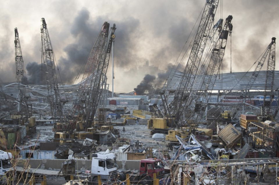 Smoke billows into the sky over Beirut in the aftermath, with considerable structural damage in the proximity of the explosion.