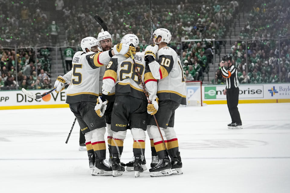 Vegas Golden Knights players surround Noah Hanifin after he scored against the Dallas Stars during the second period in Game 2 of an NHL hockey Stanley Cup first-round playoff series in Dallas, Wednesday, April 24, 2024. (AP Photo/Tony Gutierrez)