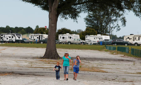 Stephanie Giordano (C) walks with her grandson four year old Brayden Screen (L) and her son Sam Giordano in front of several trailers after originally driving from Savannah, Goergia to ride out Hurricane Irma at Atlanta Motor Speedway in Hampton, Georgia, U.S., September 10, 2017. REUTERS/Tami Chappell