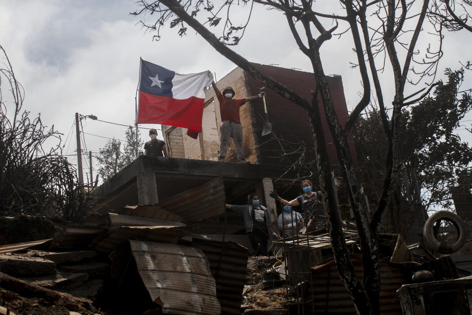 Un residente agarra una bandera de Chile sobre los restos de una vivienda arrasada por las llamas, en Viña del Mar, Chile, el 4 de febrero de 2024. (AP Foto/Cristobal Basaure)