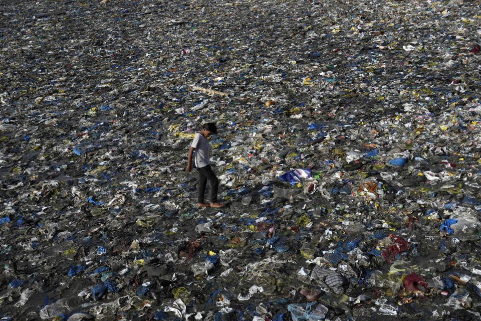 FILE - A boy walks on the plastic waste at the Badhwar Park beach on the Arabian Sea coast on World Environment Day in Mumbai, India, June 5, 2023. (AP Photo/Rajanish Kakade, File)