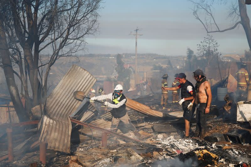 People help firefighters as they work to extinguish a fire in Valparaiso