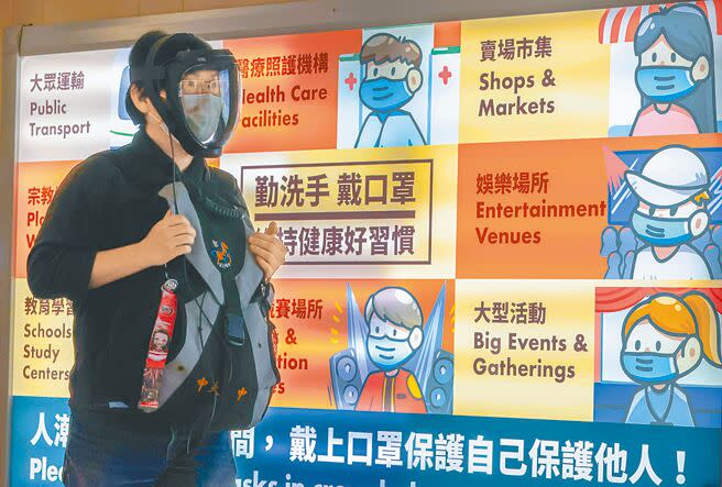 台灣17日新增逾6萬新冠肺炎確診本土病例，美國疾病管制暨預防中心（CDC）16日將台灣的疫情風險等級，從第二級的「中度風險」調升至風險最高的「第三級」。圖為桃園機場一位入境旅客載著口罩加上面罩走過機場入境長廊的防疫看板前。（陳麒全攝）