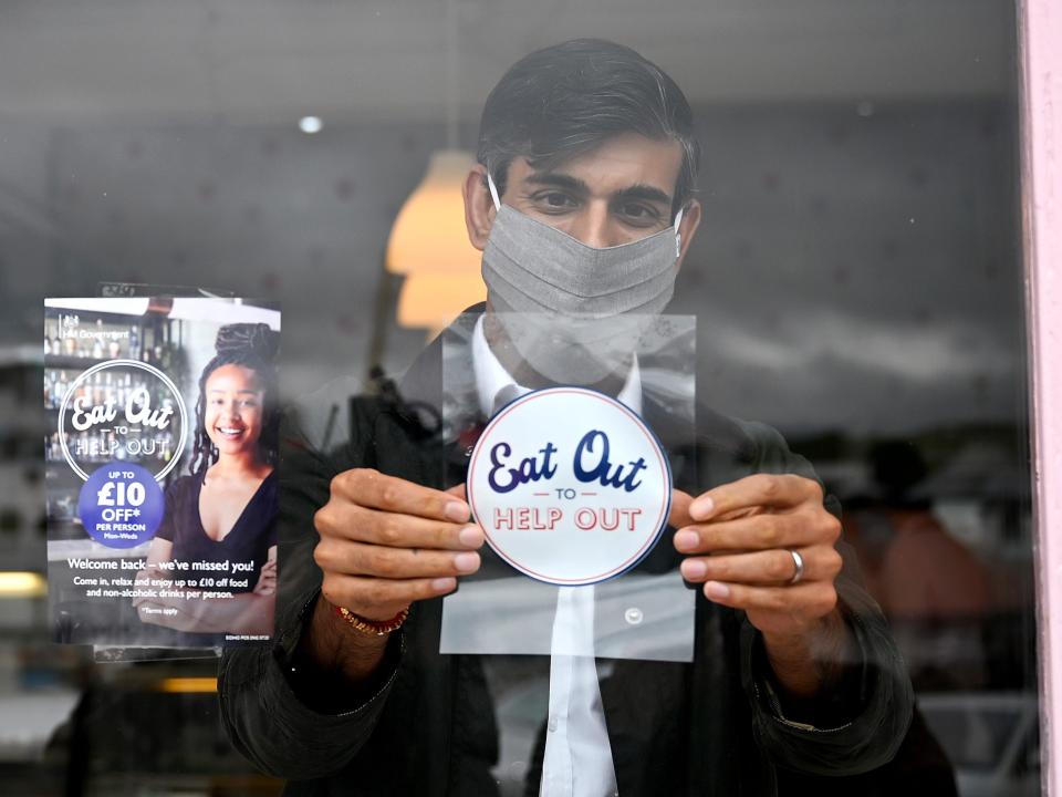 Rishi Sunak puts an Eat Out to Help Out sticker in a restaurant window during a visit to Rothesay on the Isle of Bute, Scotland in August 2020.