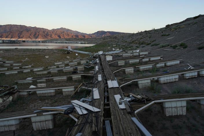 Floating boat docks sit on dry ground as water levels have dropped near the Callville Bay Resort & Marina in the Lake Mead National Recreation Area, Tuesday, Aug. 30, 2022, near Boulder City, Nev. As water levels plummet, calls for reduced use have often been met with increased population growth. (AP Photo/John Locher)