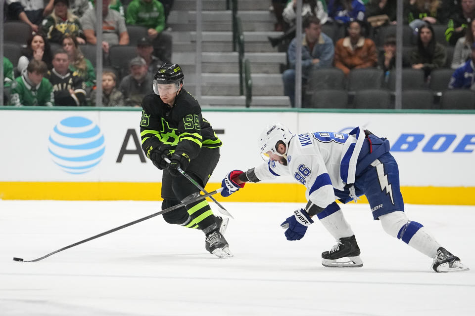 Dallas Stars defenseman Thomas Harley (55) and Tampa Bay Lightning right wing Nikita Kucherov (86) compete for possession during the first period of an NHL hockey game, Saturday, Dec. 2, 2023, in Dallas. (AP Photo/Julio Cortez)