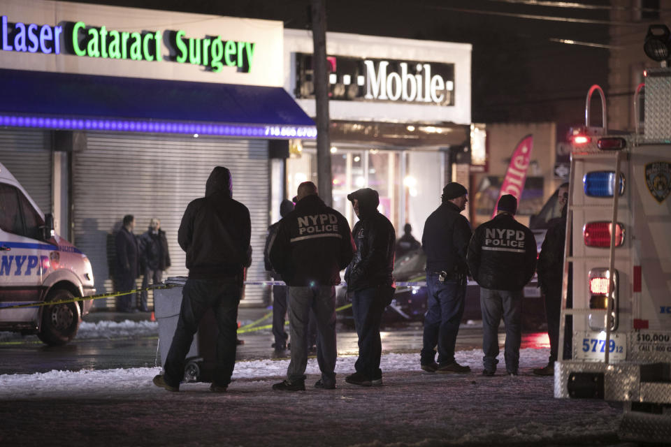 Investigators look over the area after a few New York City police officers were shot while responding to a robbery at a T-Mobile store in the Queens borough of New York on Tuesday, Feb. 12, 2019. (AP Photo/Kevin Hagen)