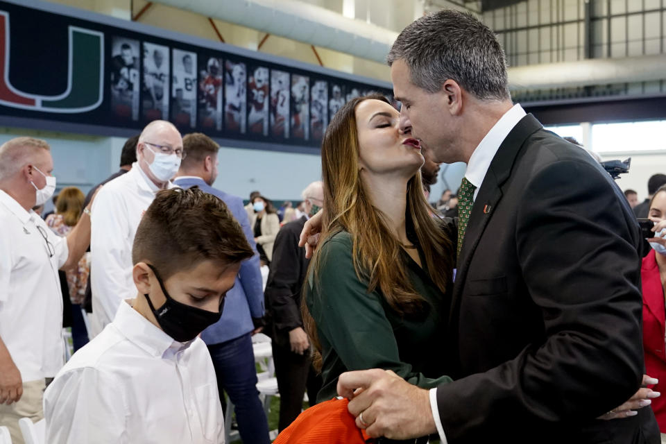 Mario Cristobal, right, kisses his wife, Jessica, after being introduced as Miami football coach during a news conference Tuesday, Dec. 7, 2021, in Coral Gables, Fla. Cristobal is returning to his alma mater, where he won two championships as a player. (AP Photo/Lynne Sladky)