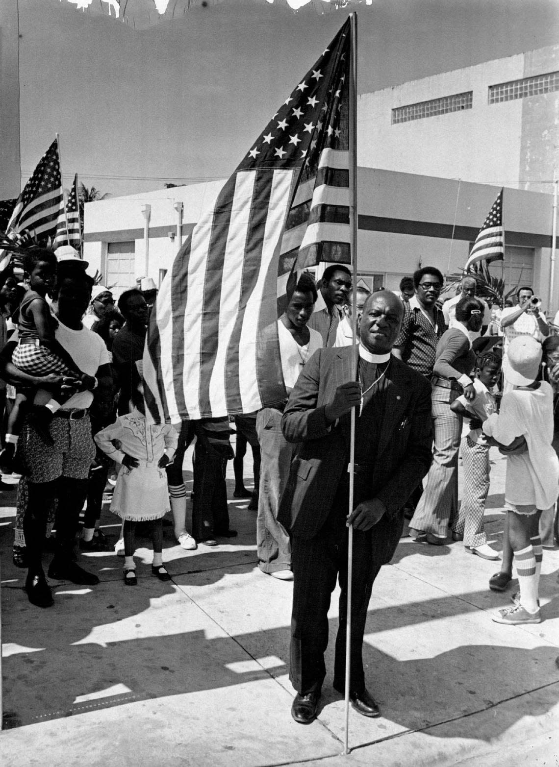 The Rev. Theodore Gibson, a Miami civil rights leader, plants a U.S. flag on one of the “four corners” at Douglas Road and Grand Avenue in the historically Black section of Coconut Grove during a Memorial Day ceremony in an undated photo. Gibson died at age 67 in 1982.