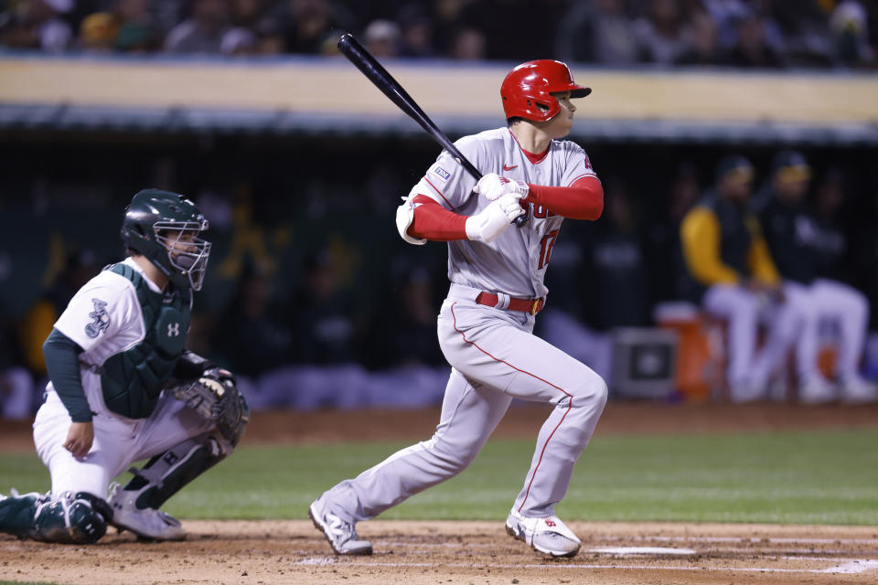 Los Angeles Angels' Shohei Ohtani, right, singles in front of Oakland Athletics catcher Shea Langeliers, left, in the fourth inning of an opening day baseball game in Oakland, Calif., Thursday, March 30, 2023. (AP Photo/Jed Jacobsohn)