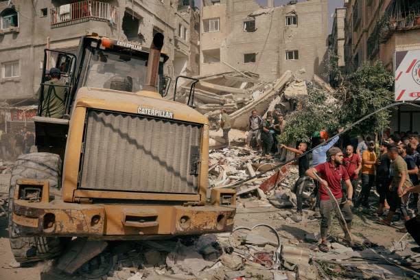 People gather around a building demolished by Israeli airstrikes to rescue injured civilians and retrieve bodies from the rubble (AFP via Getty)