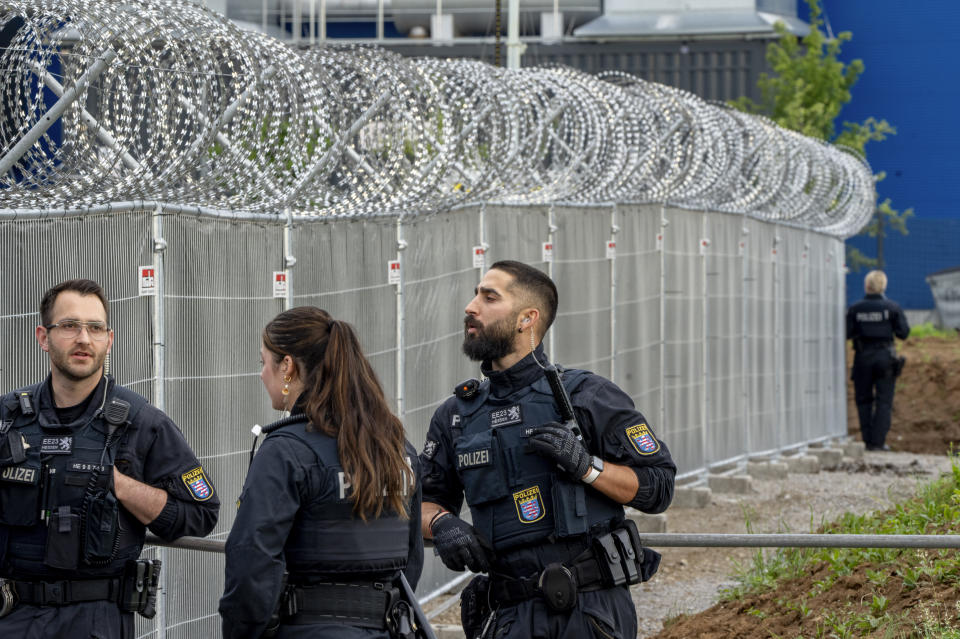 German police officers stand under barbed wire securing a temporary courtroom that was built for a trial starting on Tuesday in Frankfurt, Germany, Tuesday, May 21, 2024. The alleged leaders of a suspected far-right plot to topple the German government are among nine suspects going on trial in Frankfurt Tuesday, opening the most prominent proceedings in a case that shocked the country in late 2022. (AP Photo/Michael Probst)