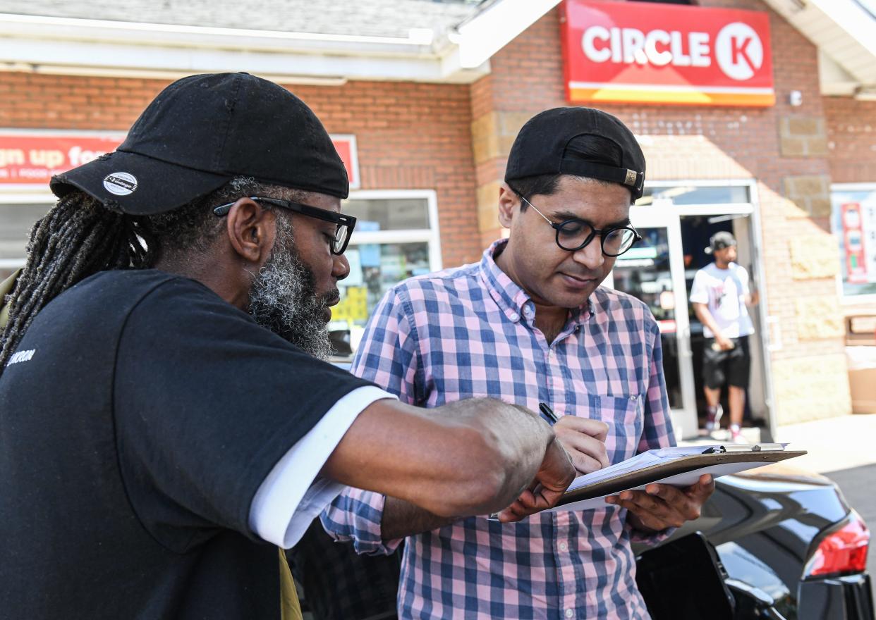 Olori Manns, left, helps Safi Syed fill out a form to get him registered to vote at a gas station in Akron. Manns is doing voter registration for Freedom BLOC.