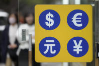 People walk near a sign of foreign currency outside a money exchange office at a shopping district in Seoul, South Korea, Tuesday, April 11, 2023. Stocks were mostly higher in Asia on Tuesday after a mixed session on Wall Street dominated by speculation the Federal Reserve may tap the brakes again on financial markets and the economy by raising interest rates. (AP Photo/Lee Jin-man)