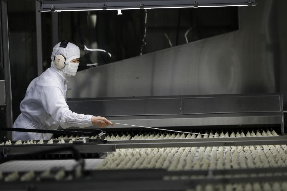 In this July 18, 2018, photo, a worker inspects dumplings on a conveyor belt to pick out a defective product at an automated factory of CJ CheilJedang Corp. in Incheon, South Korea. South Korea’s largest food company is making a multimillion-dollar bet on “mandu,” developing its own machines to automate the normally labor-intensive production of the Korean dumpling and building factories around the world. (AP Photo/Lee Jin-man)