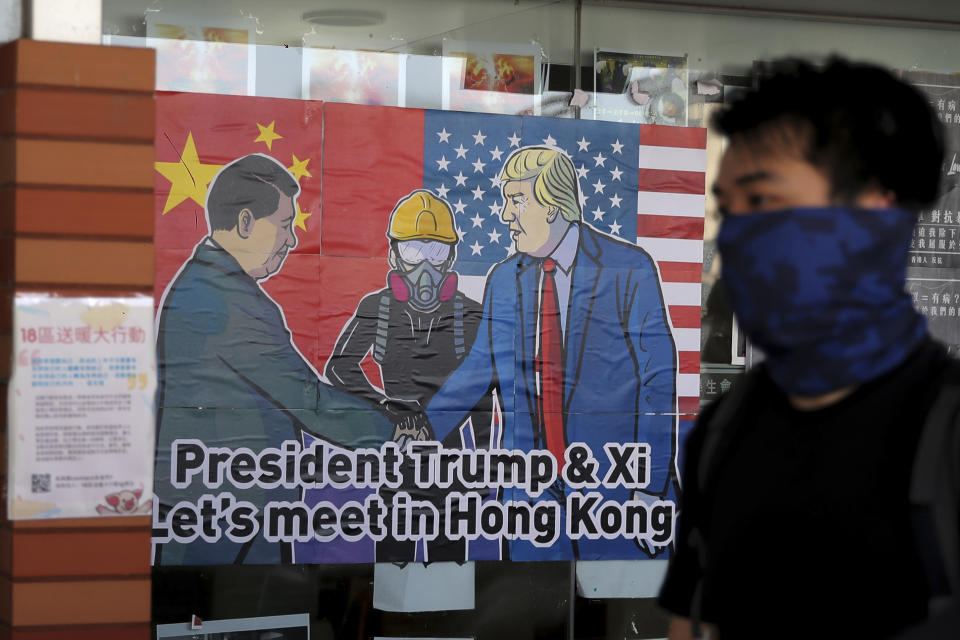 A pro-democracy university student walks past a poster featuring Chinese President Xi Jinping and U.S. President Donald Trump at the campus of the University of Hong Kong, Wednesday, Nov. 6, 2019, as they against police brutality. The protests began in early June against a now-abandoned extradition bill that would have allowed suspects to be sent for trials in mainland China, which many saw as infringing of Hong Kong's judicial freedoms and other rights that were guaranteed when the former British colony returned to China in 1997. The movement has since grown into calls for greater democracy and police accountability. (AP Photo/Kin Cheung)