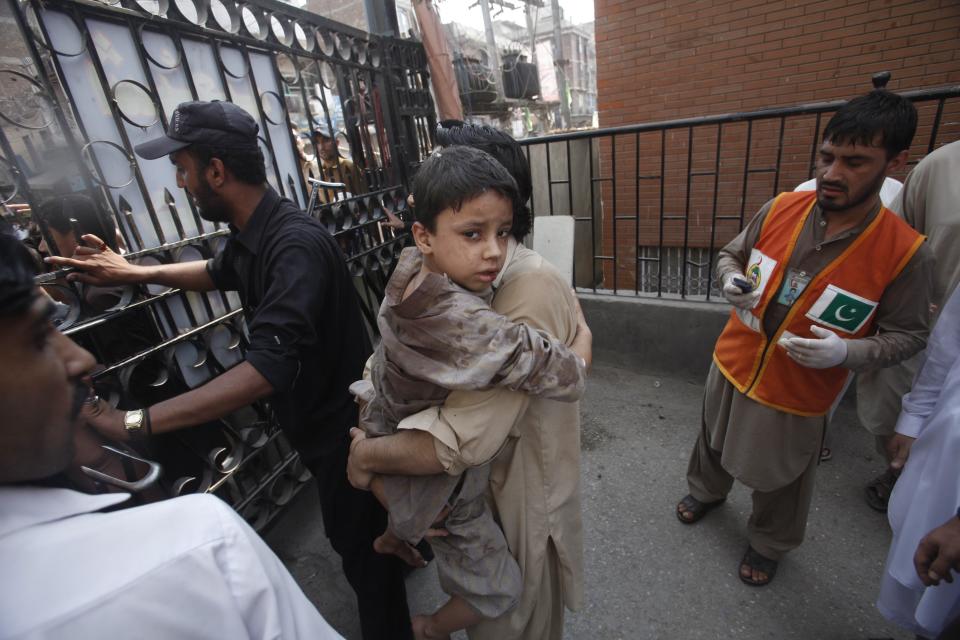 Man carries his son, who was injured in a bomb blast as he arrives at a hospital in Peshawar