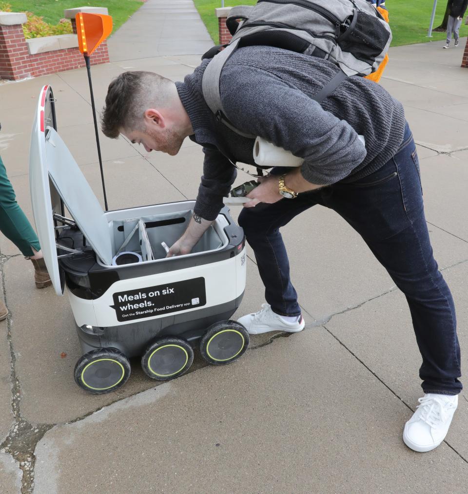 Starship Technologies project manager Joe Maloney shows off the inside of a Starship Food Delivery robot at the University of Akron.