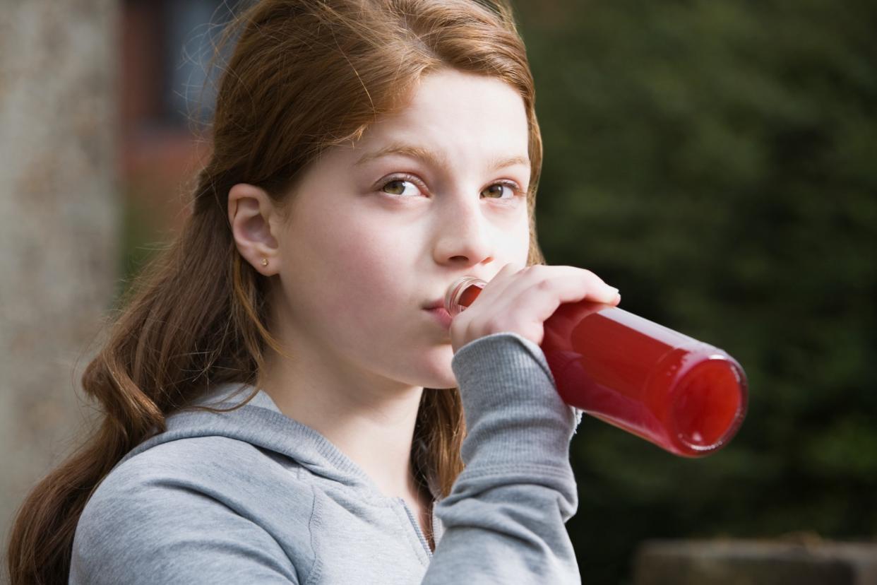 Teenage girl holds a bottle to her lips