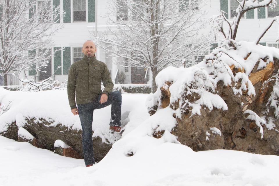 Garrett Roberson stands next to a fallen tree on the front lawn of the McPherson Mansion in downtown Howell Wednesday, Feb. 2, 2022. He plans to use lumber from the tree to make a boardroom table and other furniture for a conference room in the office building.