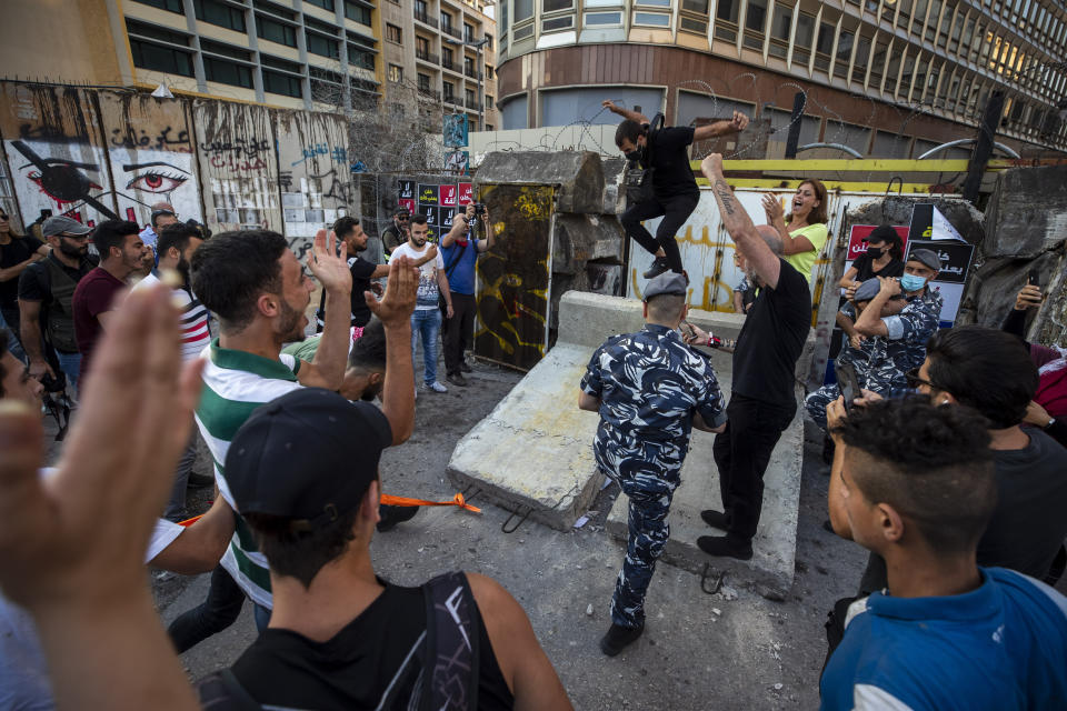 Anti-government protesters celebrate after they removed part of a concrete wall that was installed by security forces to prevent them from reaching the government palace in Beirut, Lebanon, Thursday, July 2, 2020. Major retailers in Lebanon announced Thursday they will temporarily close in the face of an increasingly volatile currency market and their inability to set prices while the local currency tumbles before the dollar. (AP Photo/Hassan Ammar)