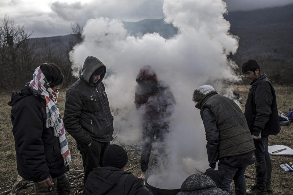 In this picture taken Wednesday Dec. 11, 2019, a group of refugees from Afghanistan cook in the mountains surrounding the northern Bosnia town of Bihac after they fled a makeshift camp cleared and destroyed by Bosnian police near the village of Vucjak to avoid being resettled, in the outskirts of Bihac, northwestern Bosnia.(AP Photo/Manu Brabo)