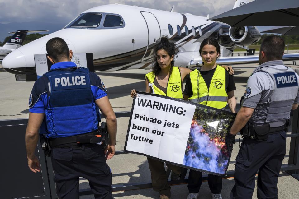 FILE - Environmental activists of Stay Grounded and Greenpeace protest in front of an aircraft during the European Business Aviation Convention and Exhibition (EBACE), at the Geneve Aeroport in Geneva, Switzerland, May 23, 2023. Climate activists have spraypainted a superyacht, blocked private jets from taking off and plugged holes in golf courses this summer as part of an intensifying campaign against the emissions-spewing lifestyles of the ultrawealthy. (Laurent Gillieron/Keystone via AP, File)