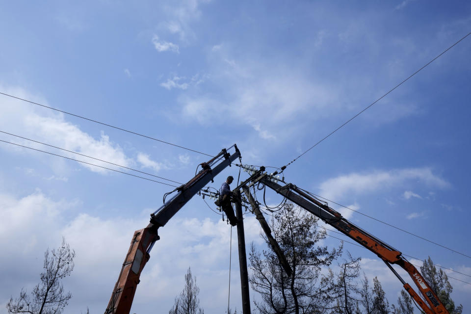 A worker is seen fixing an electricity power line near village Milies on Evia island, about 181 kilometers (113 miles) north of Athens, Greece, Thursday, Aug. 12, 2021. Greek Prime Minister Kyriakos Mitsotakis says the devastating wildfires that burned across the country for more than a week amount to the greatest ecological catastrophe Greece has seen in decades. (AP Photo/Petros Karadjias)