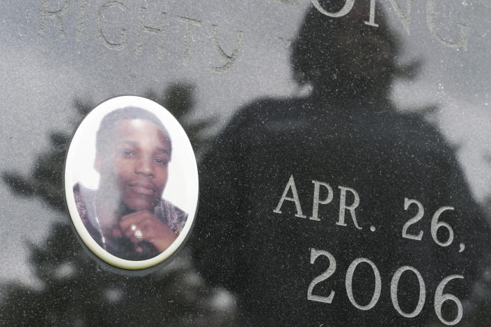Posing for a photo at a cemetery in Poughkeepsie, N.Y., April 19, 2023, Debra Long is reflected on the gravestone of her son, Randy Long, who was murdered in 2006. An AP examination of data from 23 states shows that Black people are disproportionately denied aid from programs that reimburse victims of violent crime. (AP Photo/Seth Wenig)