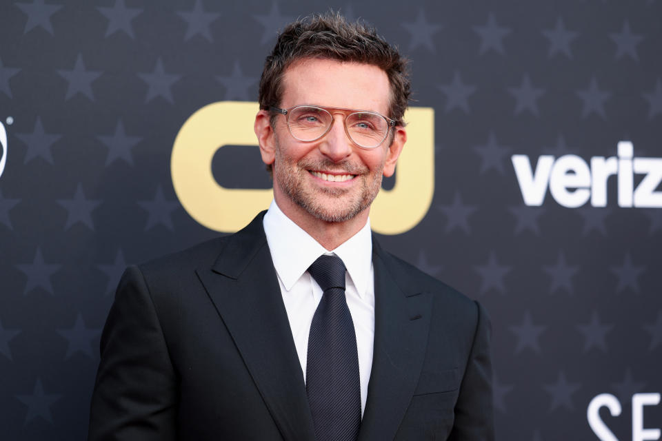 Bradley in a tailored suit with a tie smiling on a star-patterned backdrop