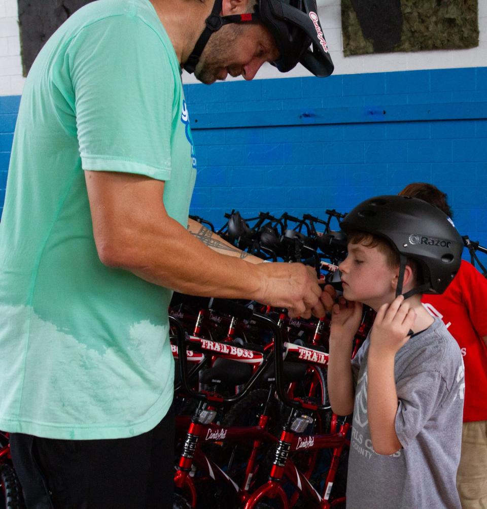 Jeff Lenosky, a professional mountain bicyclist, helps Adrian Campos, 7, put on a helmet during a bike giveaway Wednesday afternoon at the Boys and Girls Clubs of Polk County's James J. Musso Unit in Lakeland. Can'd Aid and the Yasso Game On! Foundation gave away 100 bicycles.