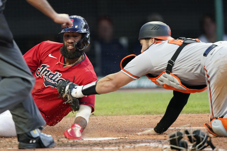 Cleveland Indians' Amed Rosario, left, scores as Baltimore Orioles catcher Austin Wynns is late on the tag in the fourth inning of a baseball game, Tuesday, June 15, 2021, in Cleveland. (AP Photo/Tony Dejak)