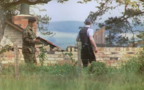 An armed police officer and a bomb disposal officer at Albert Dryden's house - Credit: REX/Shutterstock