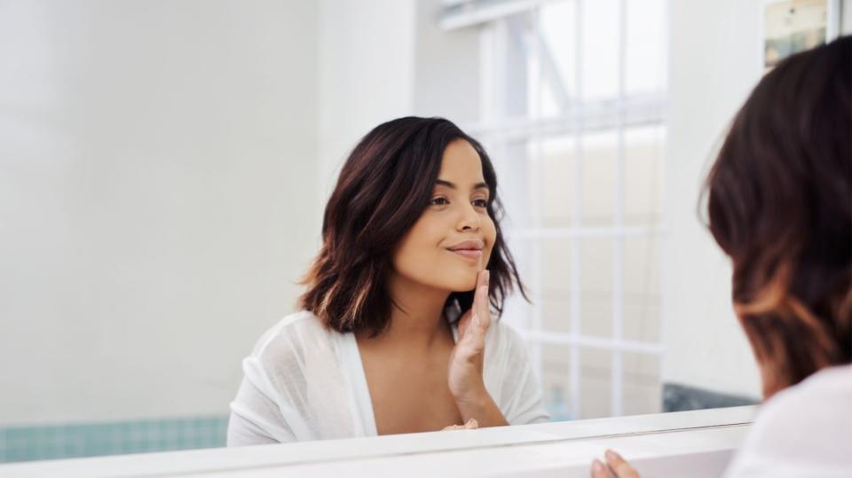 woman touching face looking in mirror